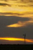 un molino en un campo con un nublado cielo foto