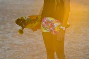 a girl holding a skateboard in the sun photo