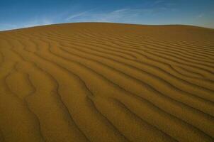 a desert with sand dunes and blue sky photo