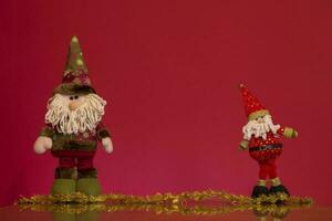 two santa claus and gnomes on a red background photo