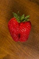 a strawberry sitting on a wooden table photo