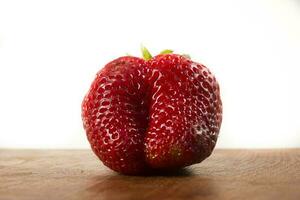 a strawberry sitting on a wooden table photo