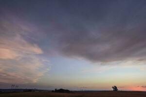 a sunset over a field with a fence and a fence post photo