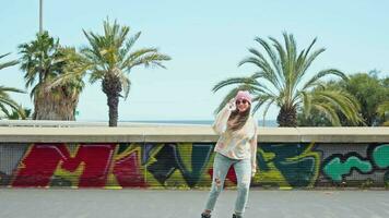 un joven mujer patinar siguiente a vibrante pintada en un pared video