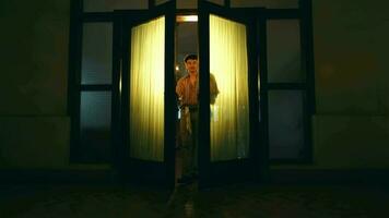 un asiatique homme des promenades et ouvre le porte de une maison équipé avec Jaune lumières video