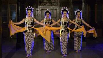 a group of Balinese dancers dance on stage playing yellow shawls video