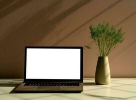 Table with vase and empty screen laptop on wallpaper photo