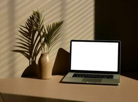 Table with vase and empty screen laptop on wallpaper photo