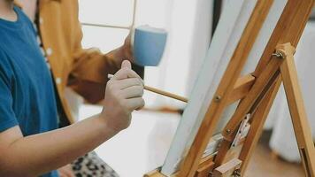 Children sister and brother playing drawing together on floor while young parents relaxing at home on sofa, little boy girl having fun, friendship between siblings, family leisure time in living room video