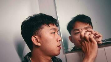 un asiatique homme est à la recherche à et en portant une miroir dans une pièce video