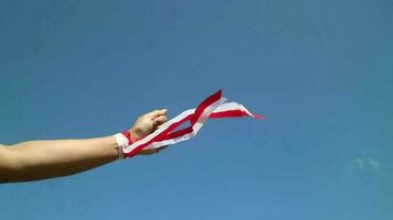 Hand with red and white ribbon with blue sky background, Indonesia independence day celebration concept video