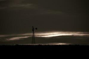 a windmill stands in the middle of a field photo