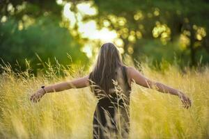 a woman standing in a field with her arms outstretched photo