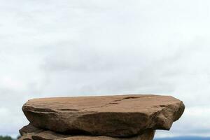 Against the background of the blue sky, a podium made of natural stone in summer nature photo