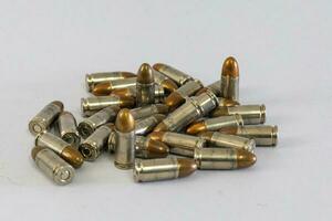 Pile of golden 9mm pistol bullets on a white background photo