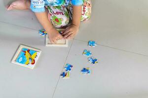 A boy sits on a jigsaw puzzle to enhance the development of a 3-year-old child. photo