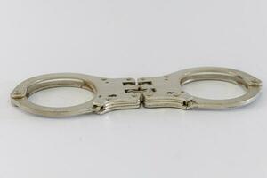 Pair of steel handcuffs isolated on white background. Silver metal handcuffs on white. photo