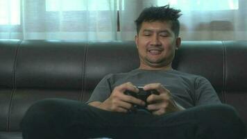 asiatique Jeune homme ayant amusement en jouant vidéo Jeux asseoir canapé à maison.asiatique Jeune homme ayant amusement en jouant vidéo Jeux asseoir canapé à maison. video