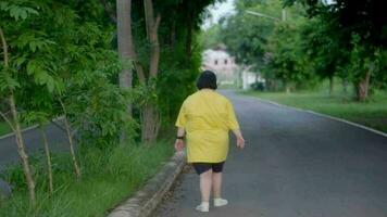 ásia mulher com baixa síndrome caminhando para exercício dentro a parque. video