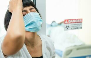 A Wife standing in front of the Quarantine room And Hold your head with her hands While waiting for the examination results, She has anxiety. Concept of Disease treatment and coronavirus vaccine photo