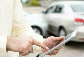 Businessman using a smartphone for taking a photo to send to insurance. Concept of claim insurance for a car accident online after send photo and evidence to the insurance company