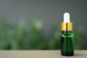 A green glass bottle with dropper on the table. Concept of aroma oil, cosmetic, and beauty skin. photo