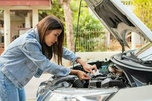 mujer asiática enojada y usando un teléfono móvil pidiendo ayuda después de una avería en el coche en la calle. concepto de problema del motor del vehículo o accidente y ayuda de emergencia de un mecánico profesional foto