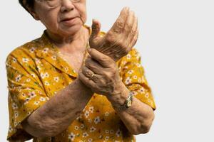 mayor asiático mujer pacientes sufrir desde entumecimiento dolor en manos desde reumatoide artritis. mayor mujer masaje su mano con muñeca dolor. concepto de articulación dolor, reumatoide artritis, y mano problemas. foto