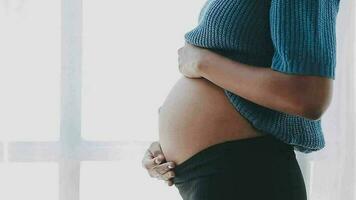 cerca arriba de asiático madre mujer demostración tramo marca suelto inferior abdomen piel ella grasa después el embarazo bebé nacimiento, estudio aislado en blanco fondo, sano barriga exceso de peso exceso cuerpo concepto video