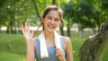 Portrait young asian woman attractive smiling and use white towel resting after workout. Smiling sporty young woman working out outdoors and looking at camera. Healthy lifestyle well being wellness photo