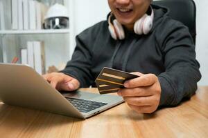 A Man holding dummy credit card and using laptop for payment online for purchase after order products via the internet. The concept of technology for e-commerce electronic commerce photo