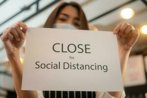 Waitress holding a sign close social distancing in a coffeeshop photo