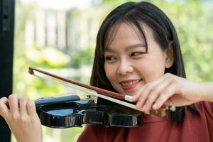 un atractivo mujer aprendizaje músico obras de teatro el violín a hogar. compositor creando canciones con cuerda instrumentos soñador violinista dedos prensado instrumentos de cuerda en violín foto