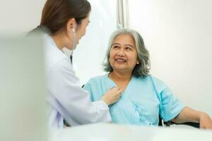 médico que examina el corazón con un estetoscopio y habla con una anciana en una clínica para revisar el chequeo anual, el servicio de atención médica y el concepto de seguro médico. foto