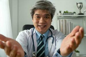 Asian doctor is online visiting with a patient on the internet application and make a note of the symptoms and explain how to treat the initial disease photo