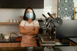 Portrait of a happy woman Asian waitress wearing a face mask and  standing at a coffee shop, Small business owner and startup with a cafe shop concept photo