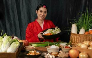 Asian women wearing Korean traditional costumes hanbok are mixing fresh stir-fry and kimchi ingredients with ingredients such as salt, garlic, gochugaru, fresh vegetables. photo