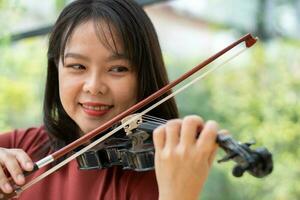 un atractivo mujer aprendizaje músico obras de teatro el violín a hogar. compositor creando canciones con cuerda instrumentos soñador violinista dedos prensado instrumentos de cuerda en violín foto