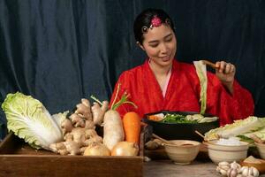 Asian women wearing Korean traditional costumes hanbok are mixing fresh stir-fry and kimchi ingredients with ingredients such as salt, garlic, gochugaru, fresh vegetables. photo