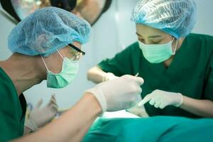 Asian Professional surgeons team performing surgery in the operating room, surgeon, Assistants, and Nurses Performing Surgery on a Patient, health care cancer and disease treatment concept photo