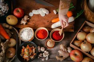 asiático mujer vistiendo coreano tradicional disfraces hanbok son mezcla Fresco Salteado y kimchi ingredientes con ingredientes tal como sal, ajo, gochugaru, Fresco vegetales. foto