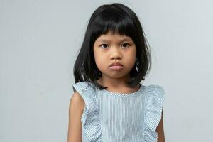 retrato de una niña asiática enojada y triste sobre un fondo blanco aislado, la emoción de un niño cuando berrinche y enojado, expresión de emoción gruñona. concepto de control emocional infantil foto