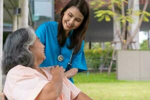 el cuidador o la enfermera asiáticos sostienen la mano del paciente y animan al paciente en silla de ruedas. concepto de jubilación feliz con el cuidado de un cuidador y ahorros y seguro de salud para personas mayores. foto