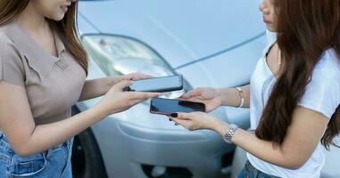 Two Drivers using a smartphone to exchange phone numbers and social media after a car accident. Concept of claim insurance for a car accident online after send photo and evidence to insurance company