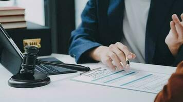 Business and lawyers discussing contract papers with brass scale on desk in office. Law, legal services, advice, justice and law concept picture with film grain effect video