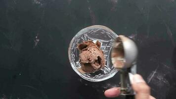 a person holding a spoon over a bowl of chocolate ice cream video