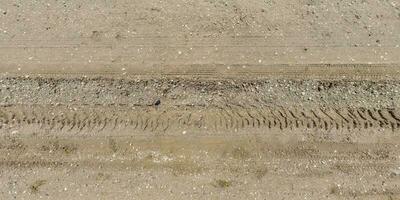 panorama of surface from above of gravel road with car tire tracks. photo