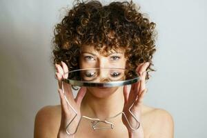 Girl with curly hair holding mirror in hands with reflection of eyes photo