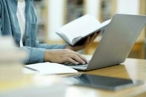 joven Universidad estudiante utilizando ordenador portátil para en línea aprendiendo, buscando y aprendizaje a biblioteca. foto