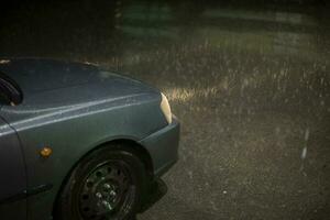 coche en lluvia. lámpara de coche brilla mediante gotas de lluvia. viaje a noche en tormenta. foto